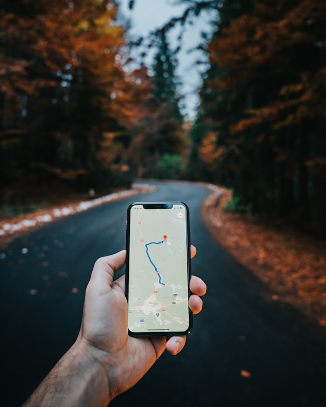 Looking at google maps while walking down a path in fall